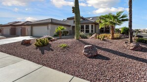 A residential house with a garage, a cactus garden, and a palm tree. - SUMMER SPECIAL SUN CITY GRAND REMODLED HOME WITH POOL (Surprise)