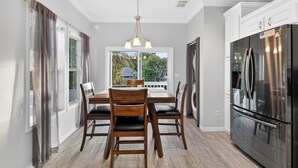 A modern kitchen with a stainless steel refrigerator, wooden dining table with chairs, and a chandelier. - SEADREAM WITH LITE BREAKFAST, HOT TUBE, AND CANAL VIEW (Stuart)