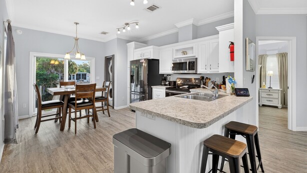 A modern kitchen with white cabinetry, a granite countertop, and stainless steel appliances. - SEADREAM WITH LITE BREAKFAST, HOT TUBE, AND CANAL VIEW (Stuart)