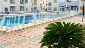 A swimming pool with a white fence, surrounded by a tiled patio. - Apartment 450 metres from Playa del Cura (Torrevieja)