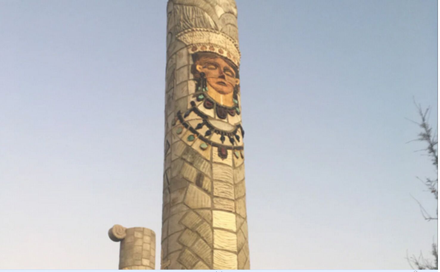 A tall, ornate column with intricate carvings and a statue at the top.