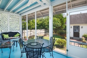 A covered patio with a round table and chairs, a wicker sofa with cushions, and a lattice screen. - Historic Song Ranch Manor (Sheffield)