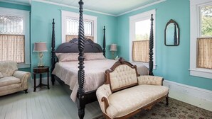 Un dormitorio con cama con dosel, una chaise longue y una pequeña mesa.