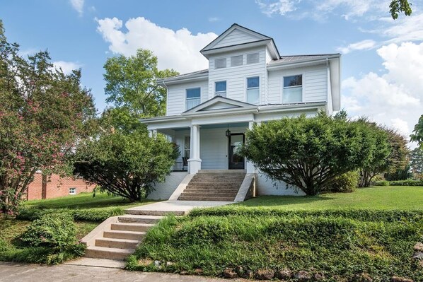 A two-story house with a front porch, a staircase leading to the front door, and a well-maintained lawn. - Historic Song Ranch Manor (Sheffield)