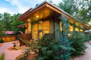 Une maison moderne dotée d’une grande véranda à l’avant, d’un porche abrité et d’un jardin bien entretenu.