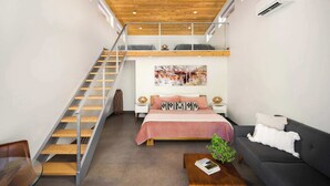 Une chambre moderne avec un lit de style industriel, un escalier, un ventilateur de plafond et une grande fenêtre.