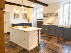 Una cocina con una isla central, armarios grises oscuros y encimera blanca.