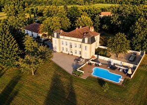 A large estate with a swimming pool, outdoor seating, and a well-maintained lawn.
