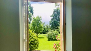 Une porte donnant sur un jardin avec un chemin de gravier et de la verdure.