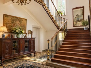 A grand staircase with ornate balusters and a wooden handrail, leading to an upper floor.