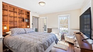 Ein Schlafzimmer mit einem großen Bett, einer Holzbücherregal, einem Fernseher und einem Fenster mit Blick.