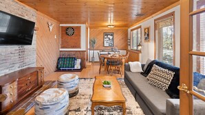 A cozy living room with a TV, wooden furniture, a dining area, and a fireplace.