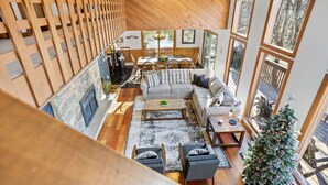 A spacious living area with a fireplace, wooden flooring, a sofa, and a Christmas tree.