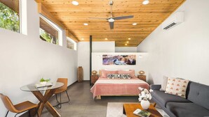 Une chambre moderne avec un lit, un canapé, une table en verre et une chaise.