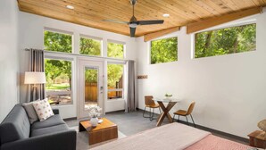 Une chambre moderne équipée d’un lit, d’un canapé, d’une table à manger et de chaises. Elle dispose de grandes fenêtres et d’un ventilateur de plafond.