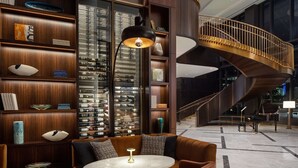 A modern interior with a curved staircase, a wine rack, and a seating area with a round table. - Conrad Nashville (Nashville)