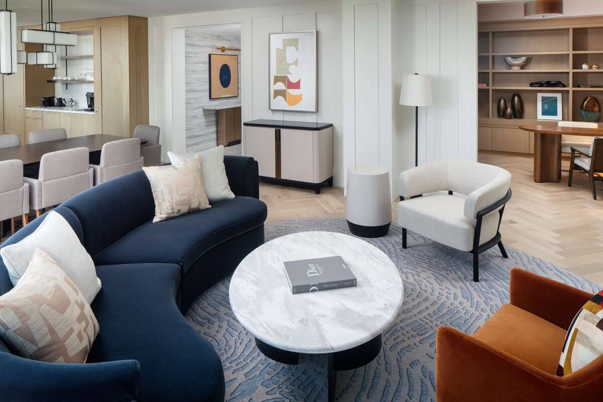 A modern living room with a sectional sofa, a round coffee table, and a dining area with a table and chairs.