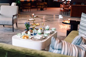 Un comedor con montaje tipo buffet, que incluye platos, vasos y una bandeja de postres escalonada.