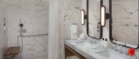 A modern bathroom with a shower, two sinks, a vanity, and a large mirror.