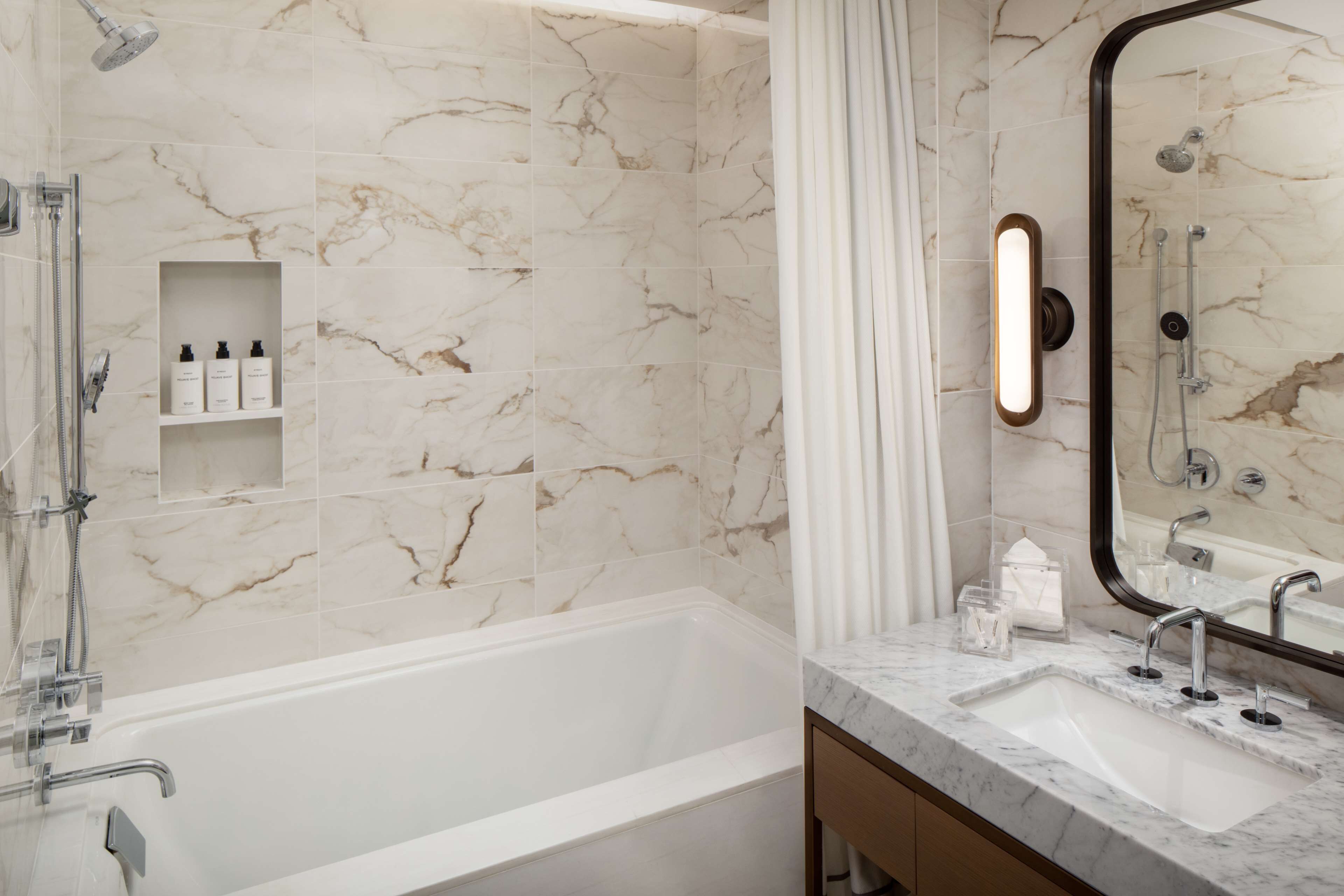A bathroom with a bathtub, a shower, and a vanity with a sink.
