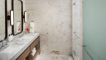 A bathroom with a marble wall, a sink with a mirror, and a shower area.