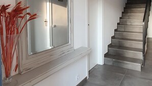 Un escalier menant à un palier agrémenté d’un grand miroir et d’un vase de plantes aux couleurs vives.