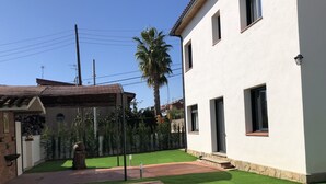 Une piscine bordée de carreaux, un bâtiment blanc doté de nombreuses fenêtres et une pelouse bien entretenue.