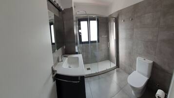 Een douche, handdoeken, zeep, toiletpapier