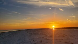 A beach at sunset with a clear sky and the sun setting over the horizon. - Gulf of Mexico Canal Cottage with Boat Dock and Heated Pool (New Port Richey)