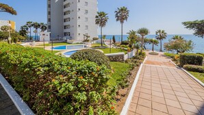 Un hotel modern amb piscina, palmeres i vistes al mar.