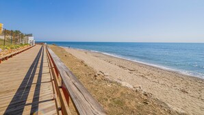Una passera de fusta que condueix a una platja sorrenca sota un cel blau i clar.