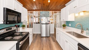 Una cocina moderna con una isla central, electrodomésticos de acero inoxidable y detalles de techo en madera.