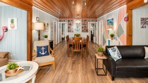 Un interior acogedor con pisos de madera, un comedor y una sala de estar con un sofá negro y un sillón a rayas.