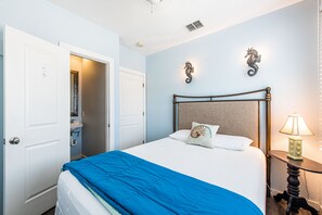 A bedroom with a bed, a nightstand, a lamp, and two decorative wall sconces.