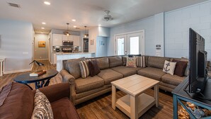 A modern living room with a sectional sofa, a coffee table, and a flat-screen TV. - Bring your Big Group, 12 BR/8 BA, Private Pool, Walk to the Beach! (Port Aransas)