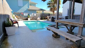 A backyard with a swimming pool, wooden deck, and picnic table. - Bring your Big Group, 12 BR/8 BA, Private Pool, Walk to the Beach! (Port Aransas)