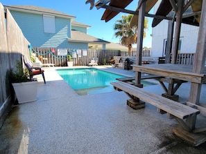 Un jardin avec une piscine, une terrasse en bois et une table de pique-nique.