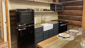 Een moderne keuken met een zwarte Galanz koelkast, een gootsteen en een houten eettafel gedekt met borden en glazen.
