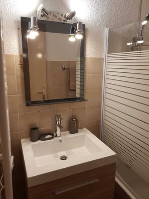 Een bad/douchecombinatie, handdoeken, zeep, toiletpapier