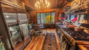 Una cocina moderna con electrodomésticos de acero inoxidable, armarios de madera y un amplio ventanal con vistas a la vegetación.