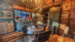 Una cocina moderna con paredes de madera, una mesa redonda para comer y sillas negras.