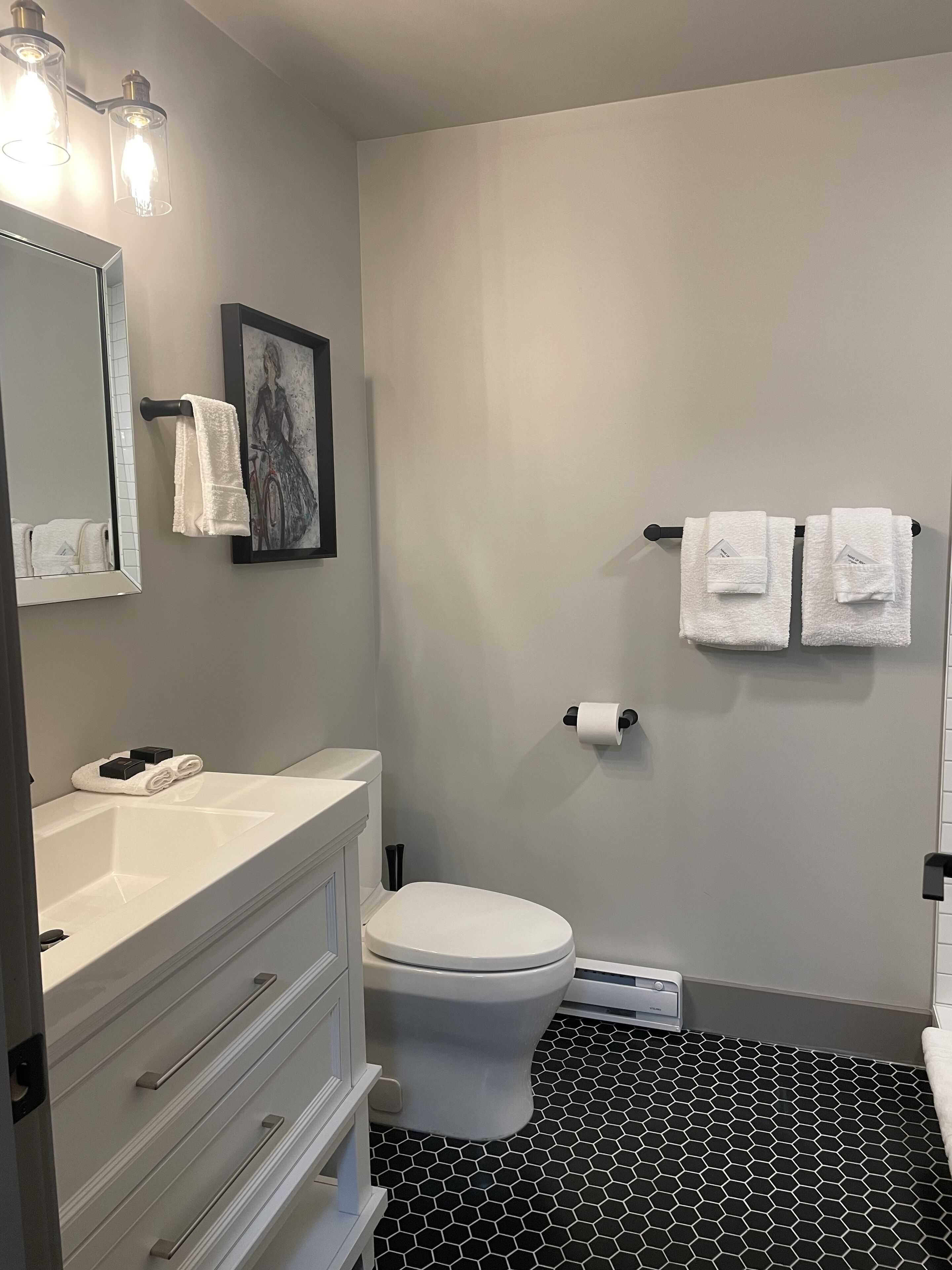 Ein Badezimmer mit weißem Waschbecken, Toilette und einem schwarz-weißen Fliesenboden.