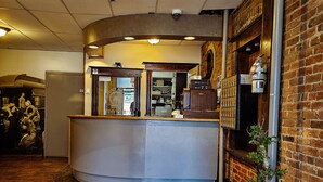 A reception area with a curved counter, a potted plant, and a brick wall. - The Baker Hotel (Cranbrook)