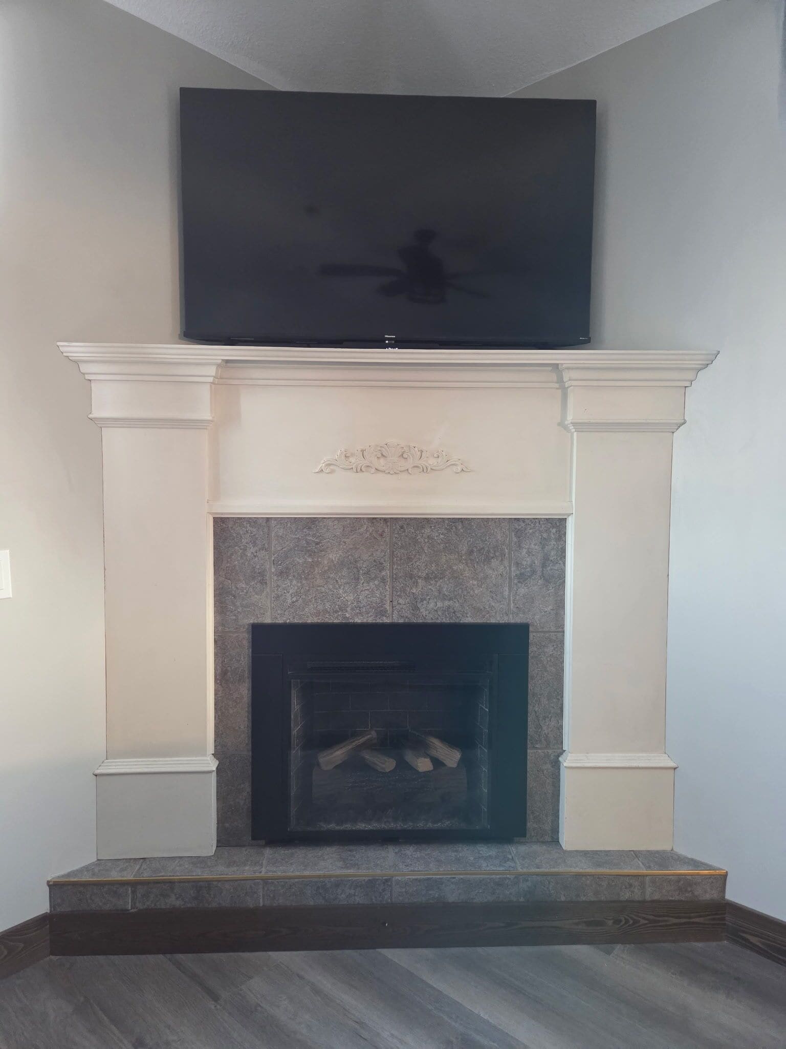Una chimenea con un televisor montado encima, un hogar de piedra y un suelo de madera oscura.