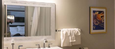 Un baño con un espejo grande, dos lavamanos, un inodoro y un ventilador de techo.