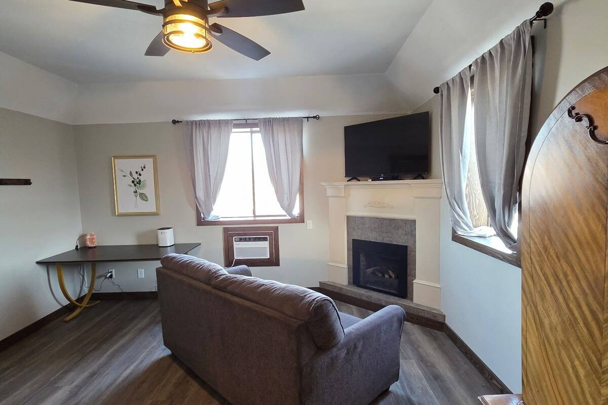 A living room with a ceiling fan, a fireplace, a television, and a sofa.