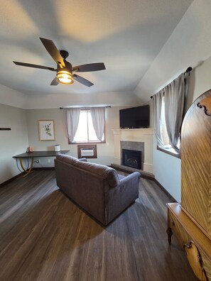 A living room with a ceiling fan, a fireplace, a television, and a sofa.