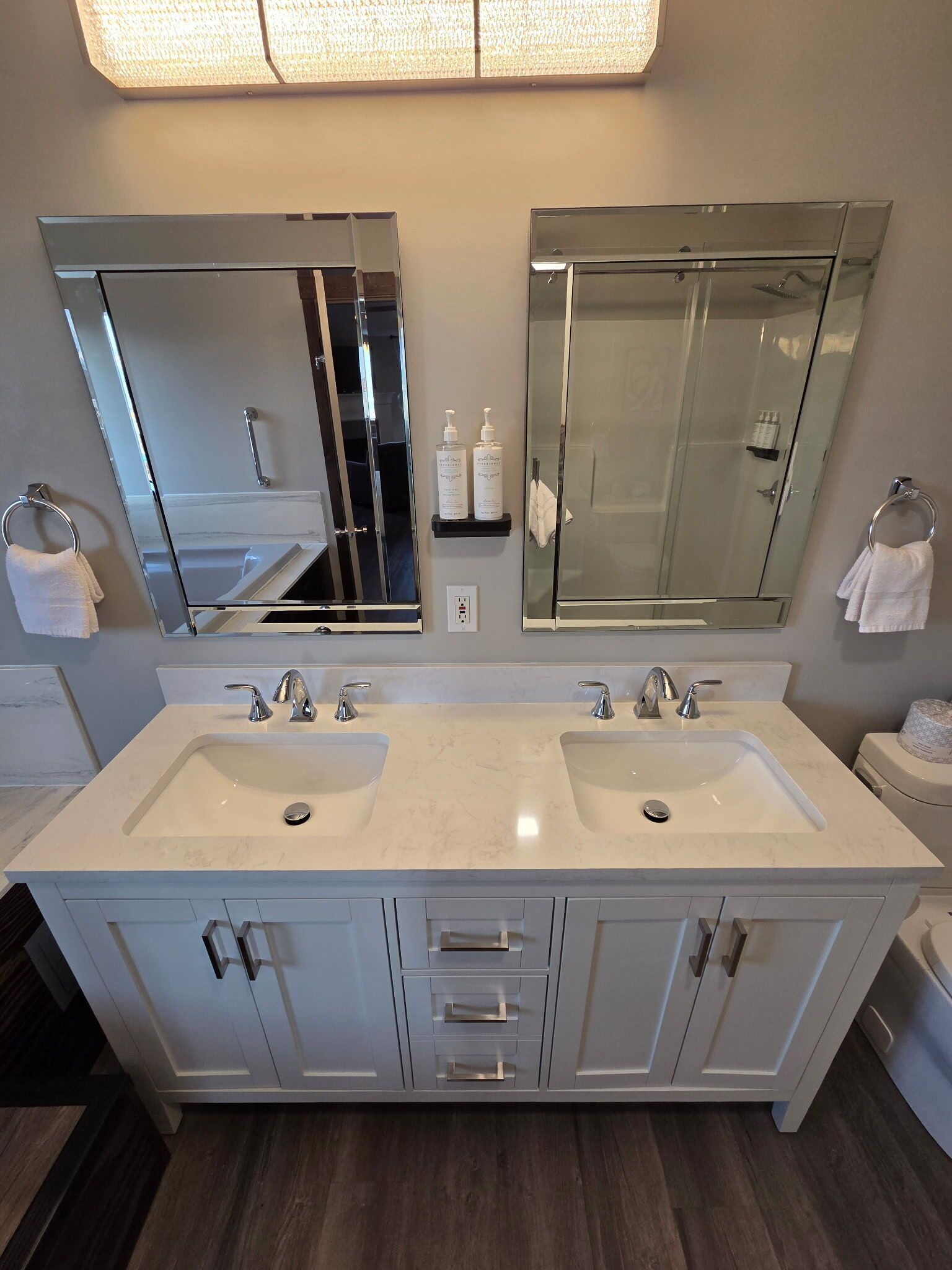 A modern bathroom with two sinks, large mirrors, and a glass shower enclosure.