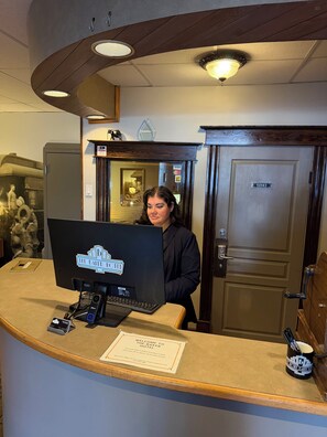 A reception desk with a computer, a welcome sign, and a door labeled 'Office'. - The Baker Hotel (Cranbrook)