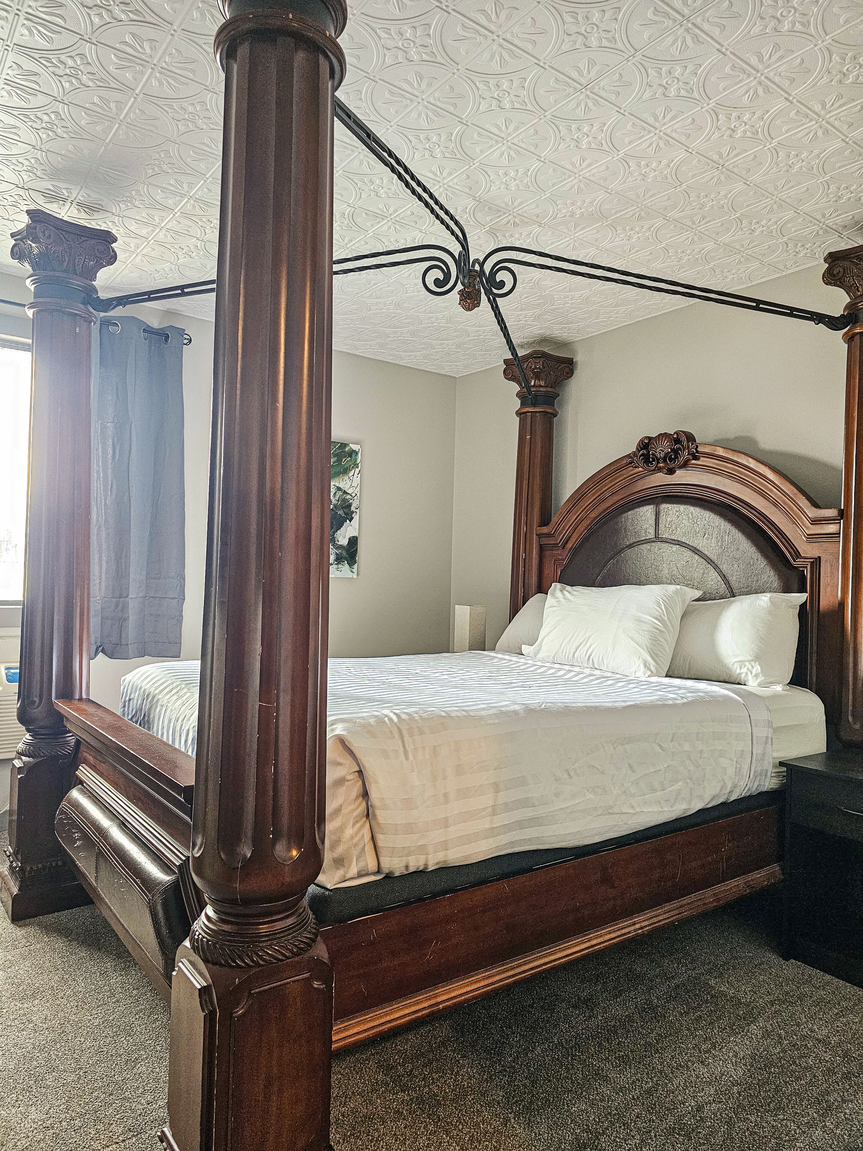 A four-poster bed with a dark wooden frame and a headboard with ornate carvings.